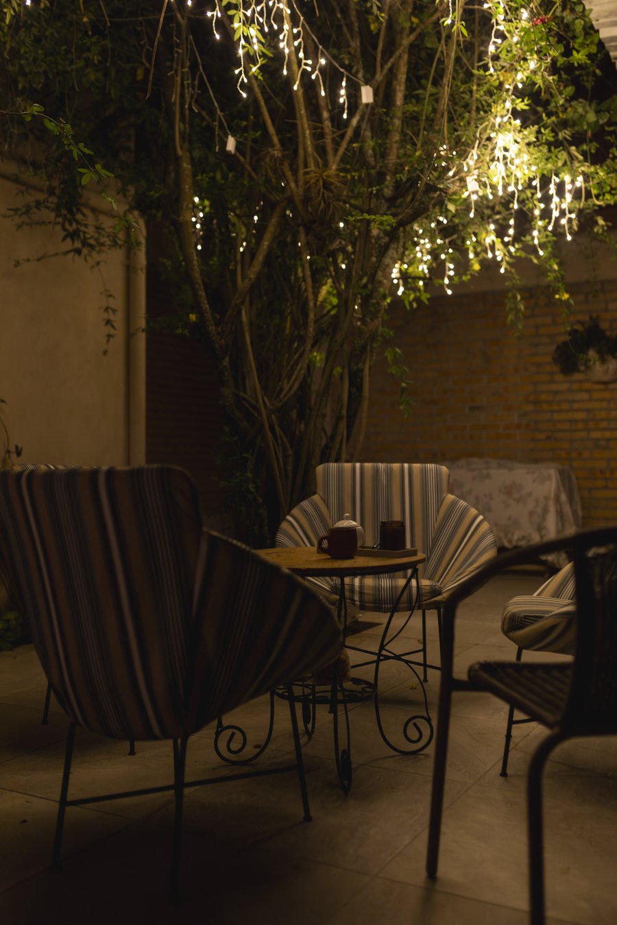 La terraza de noche, con las luces colgadas del arbol y el te servido