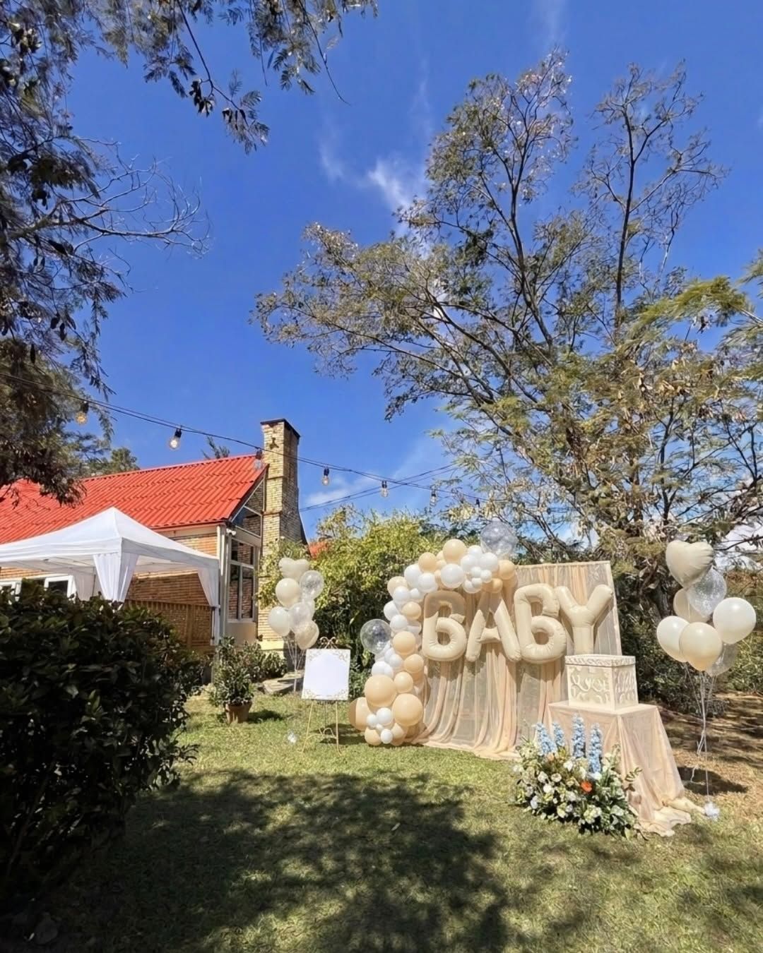 Letras BABY con globos color arena en el jardín, frente a la casa