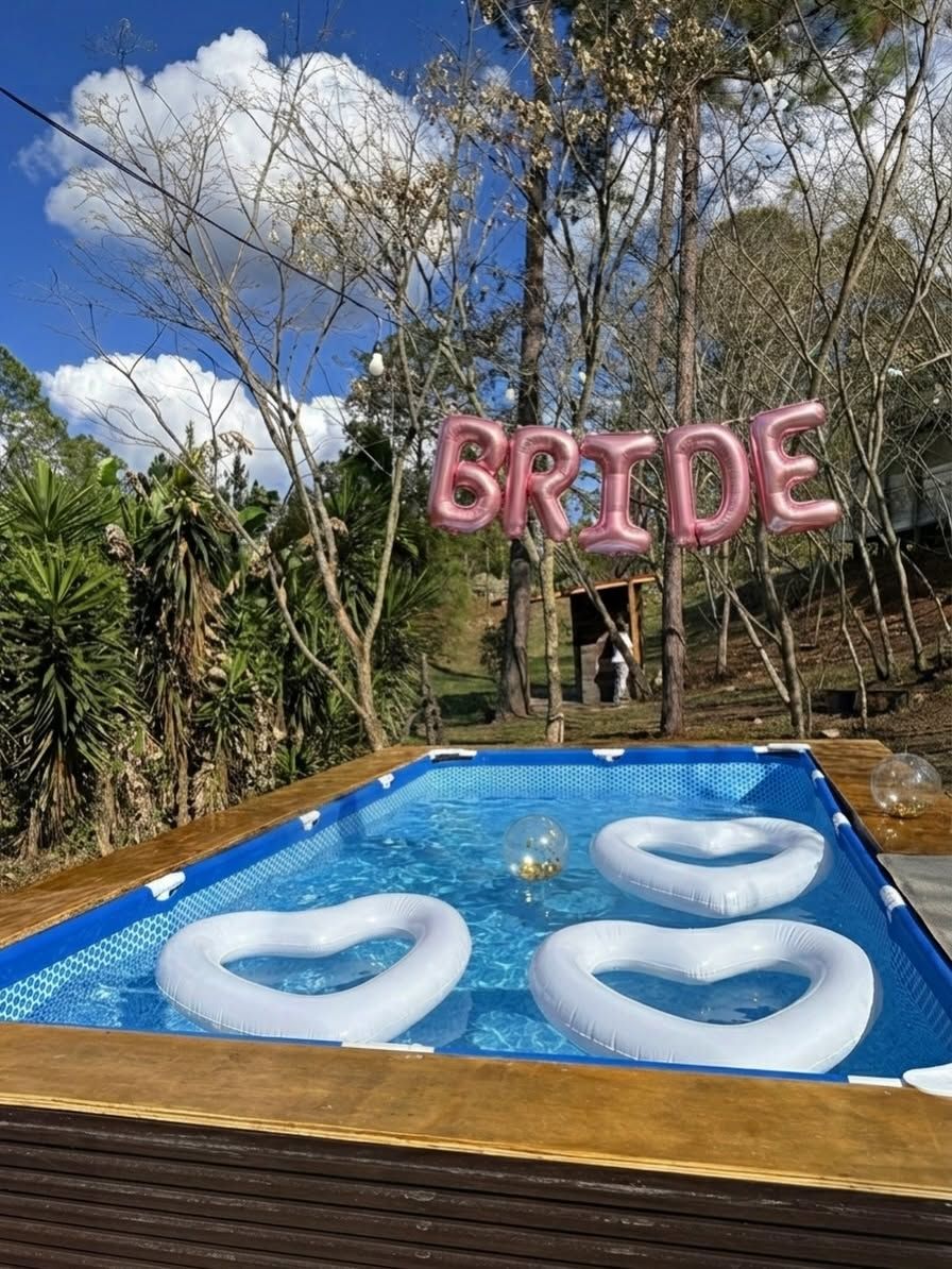 Flotadores de corazón en la piscina armable, con letras de globo que dicen BRIDE