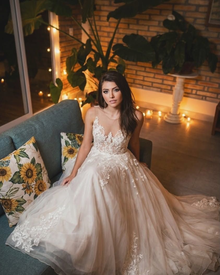 Una novia con vestido de encaje sentada en el sofá de la sala, entre velas