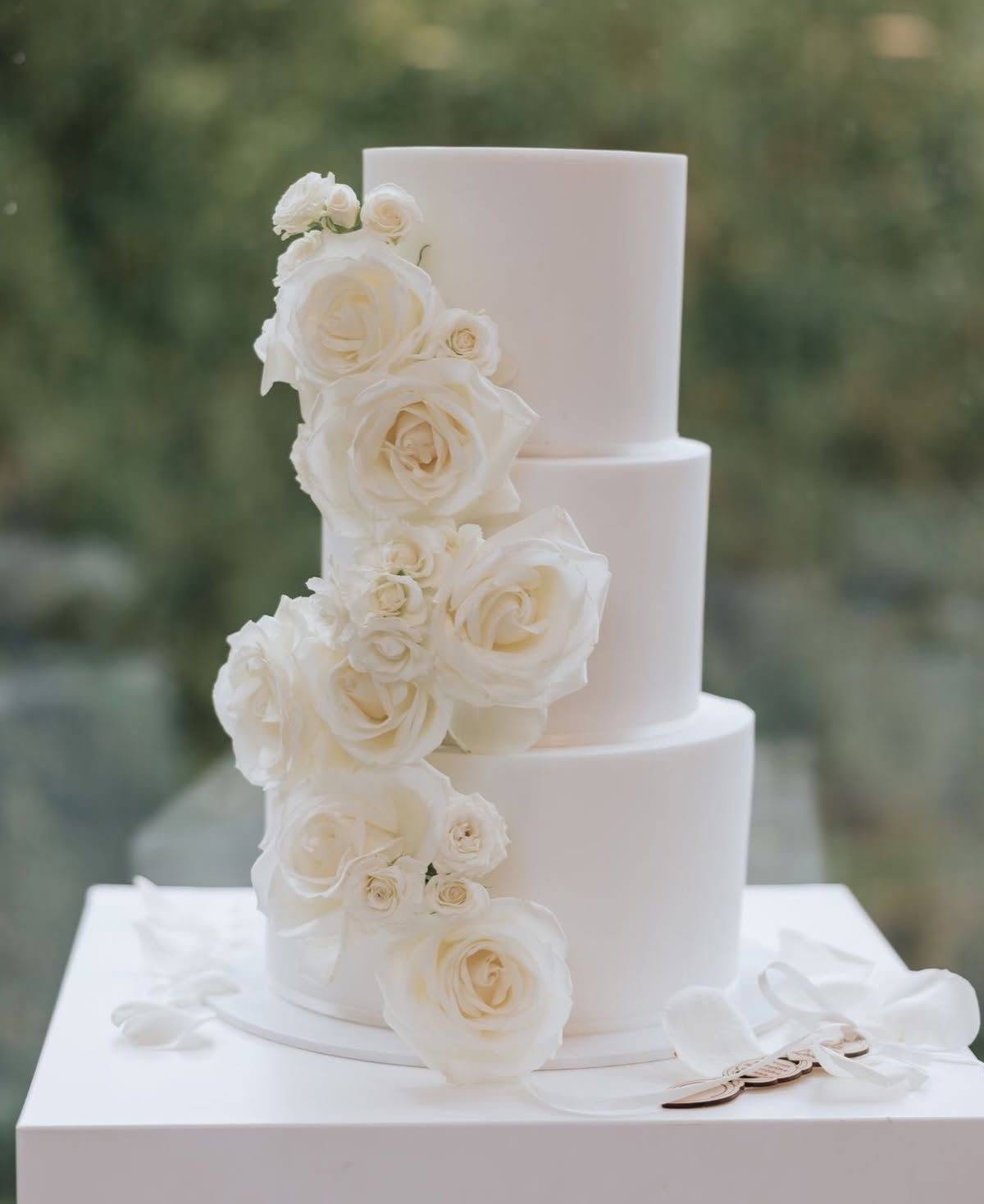 Pastel blanco de tres pisos con rosas blancas