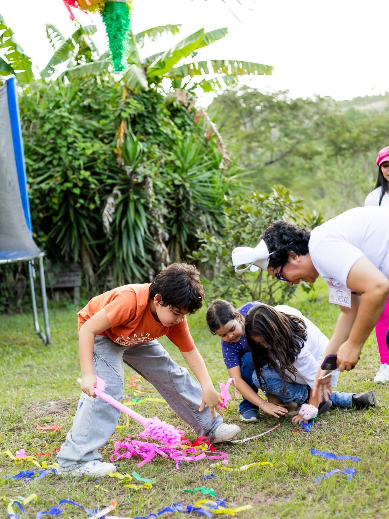 Niños recogen los dulces de la piñata entre serpentinas en el césped